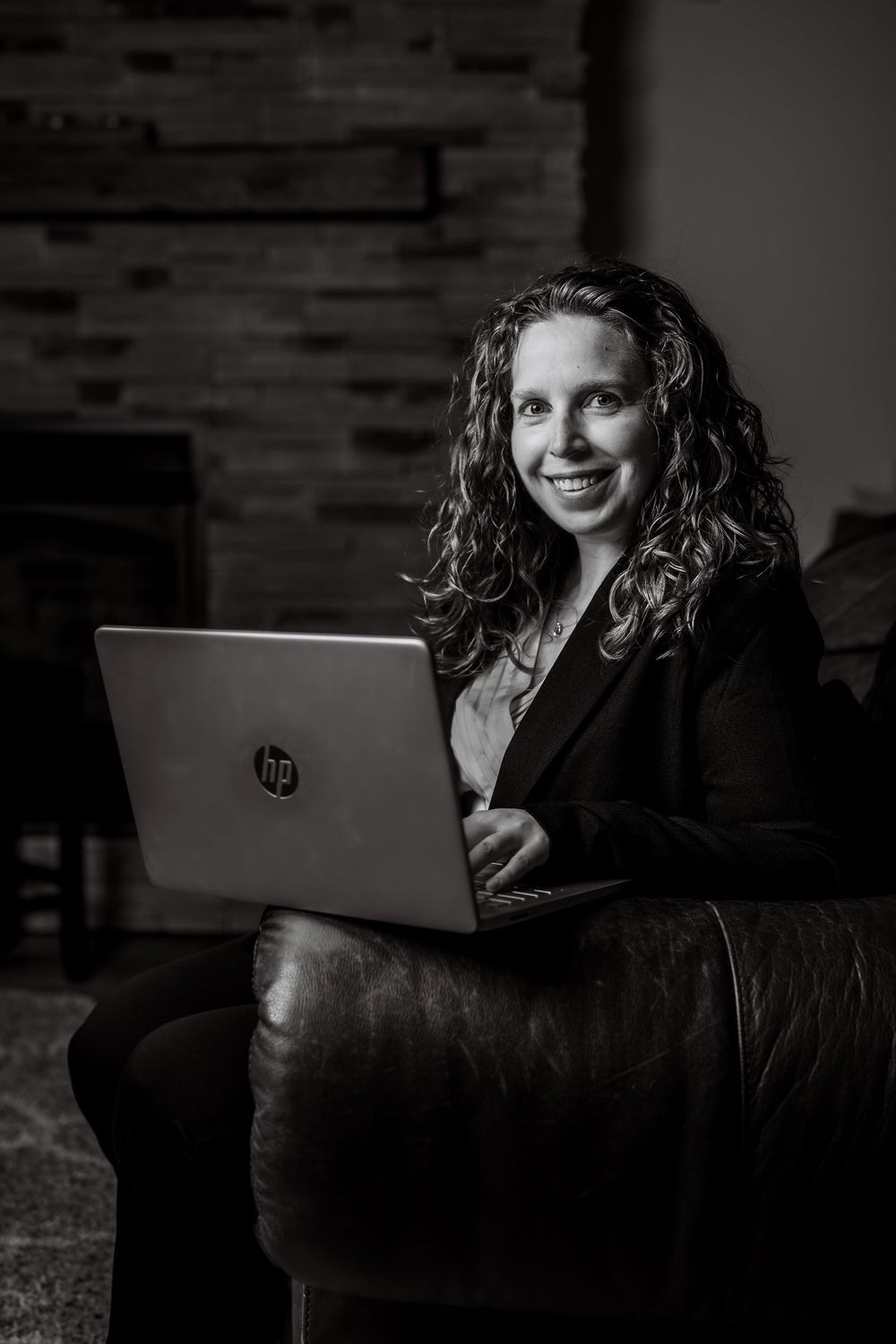 Professional headshot of woman working on laptop in modern office setting.