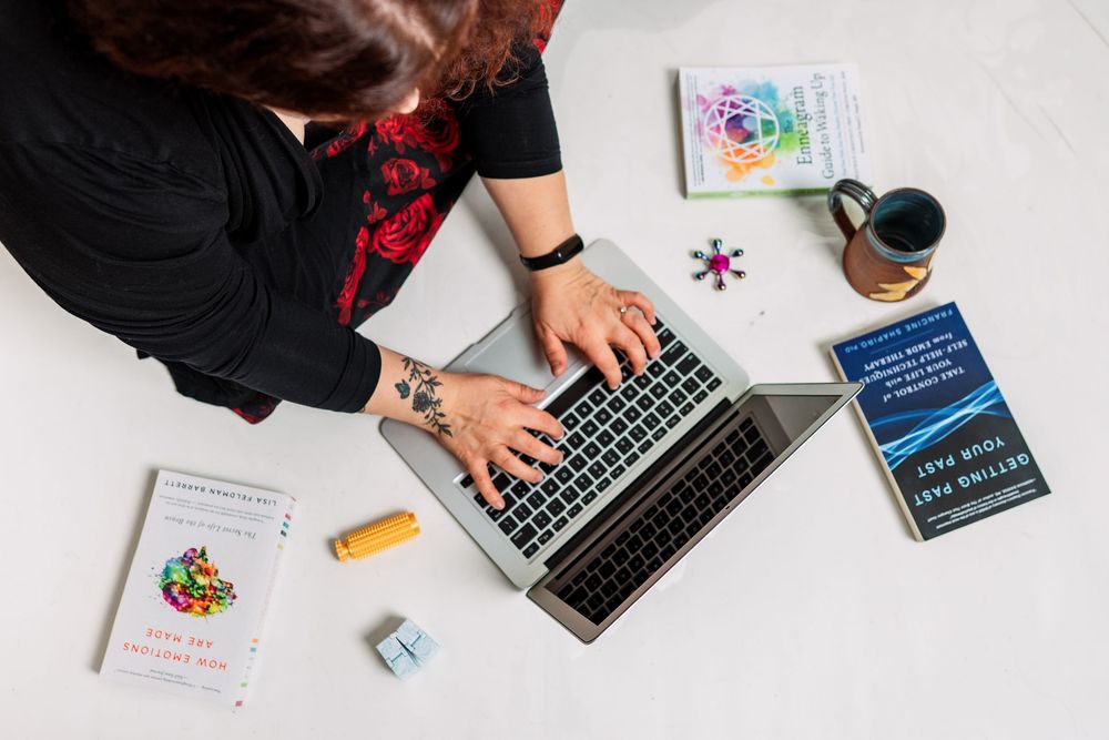 Flatlay workspace photography with laptop, books and office supplies on white surface.