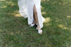 White dress hem and bare feet standing on lush green grass in a garden setting.