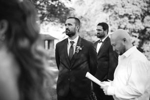 Group of formally dressed guests gathered during an outdoor wedding ceremony.