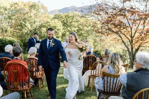 Newlyweds walking down aisle at outdoor mountain wedding ceremony.
