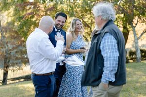 Wedding guests enjoying conversation during outdoor autumn celebration.
