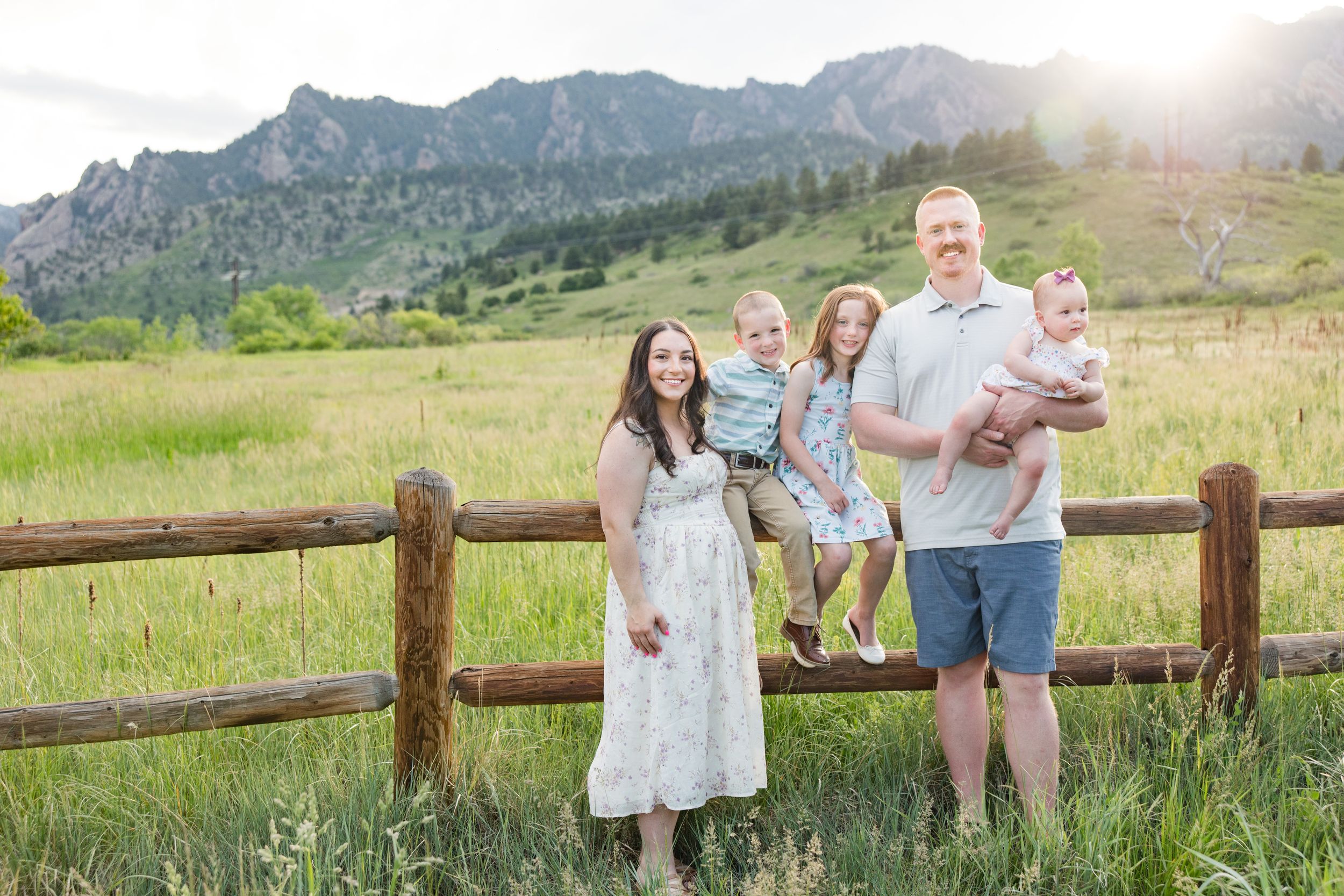 Family enjoying a sunset photoshoot against the backdrop of dramatic mountain peaks and golden meadows in Boulder, Colorado.