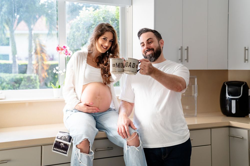 Expecting couple in kitchen holding ultrasound photos and sharing happy moment together.