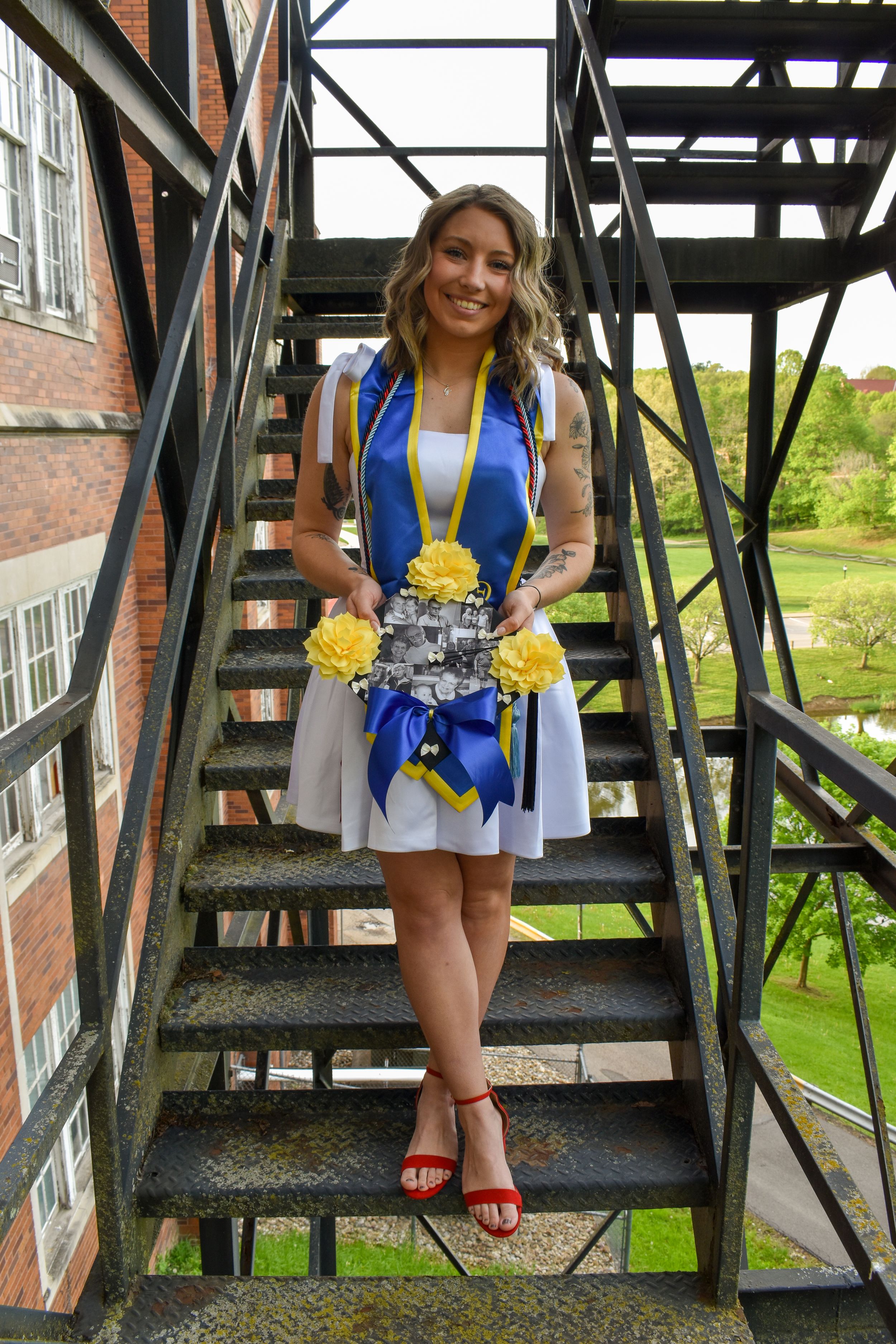 A series of outdoor iron staircase photos showing someone in a blue dress and yellow accessories posing on the steps.