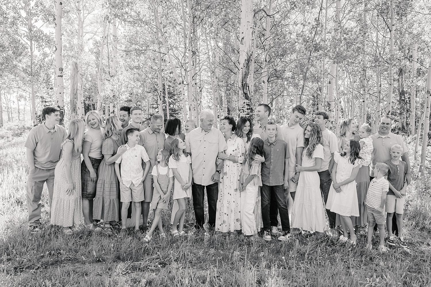 A black and white photograph of a large family group standing together in a wooded outdoor setting.