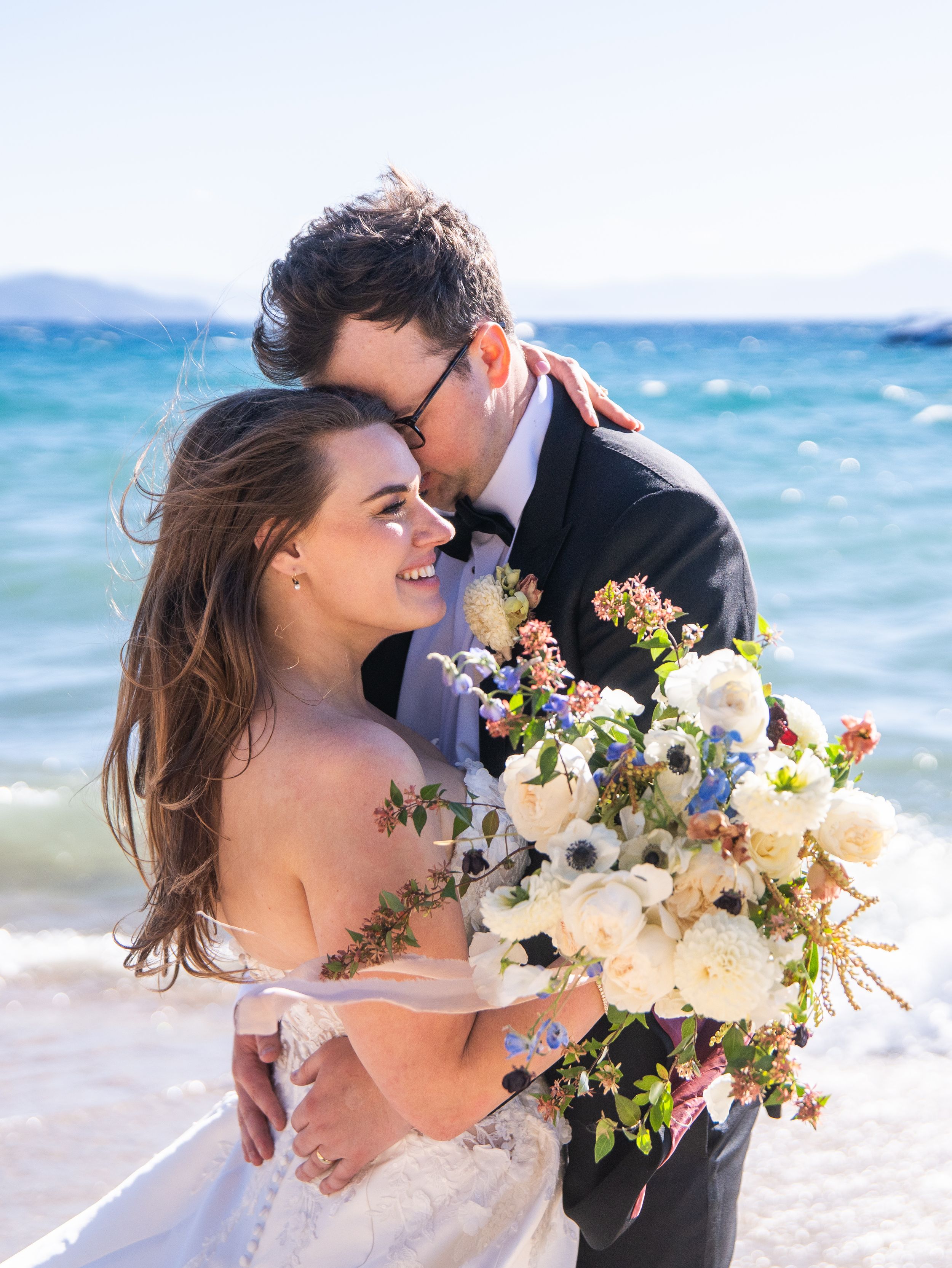 Romantic beachside scene with blue ocean waves and white floral bouquet.