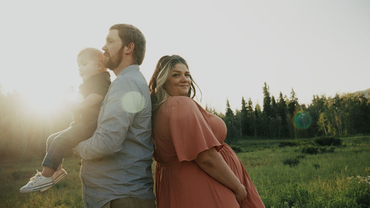 Outdoor photo shoot in field with dramatic sunset lighting and mountain backdrop.