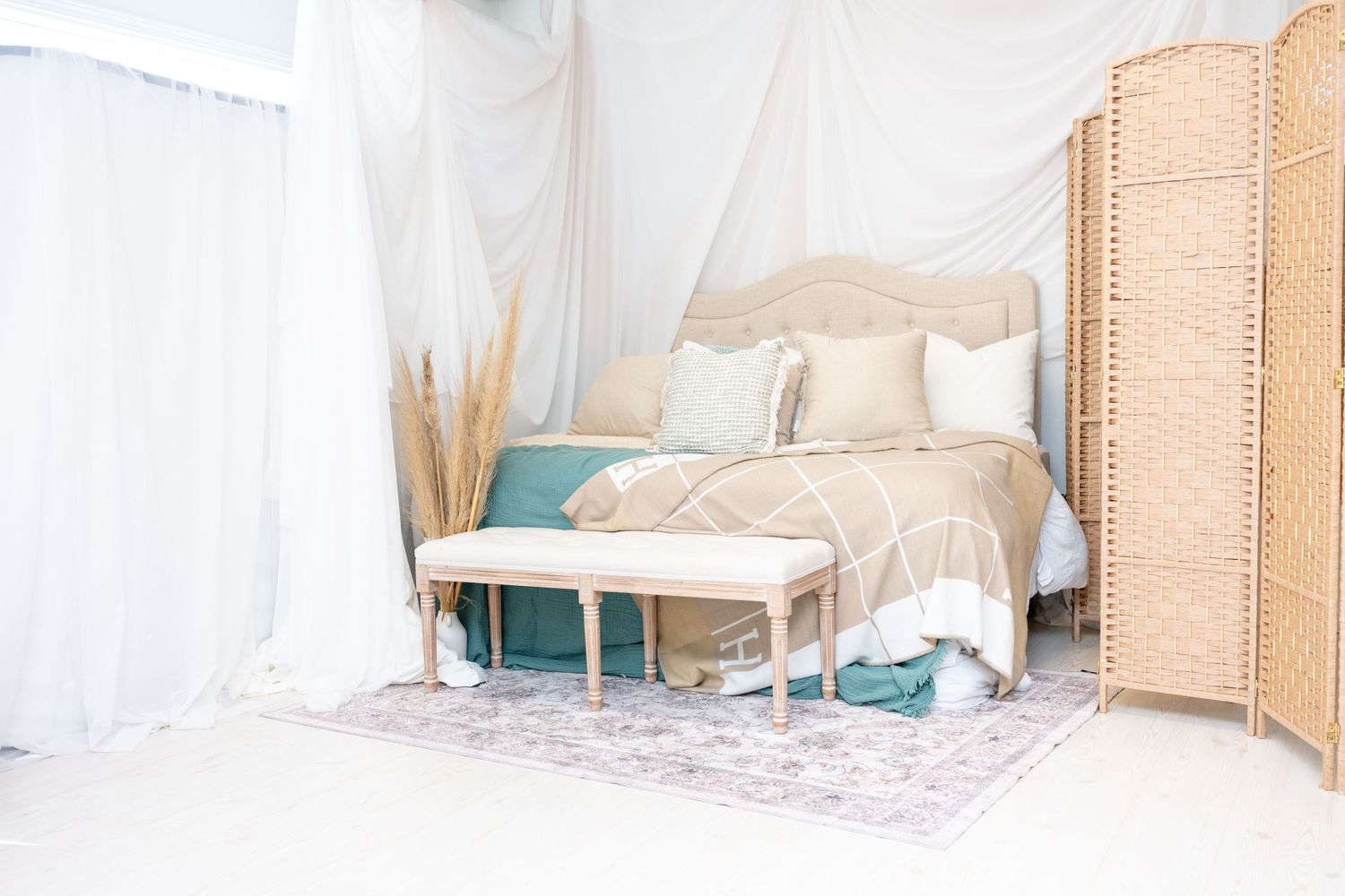 Bright photography studio bedroom set with rattan divider and white bedding.