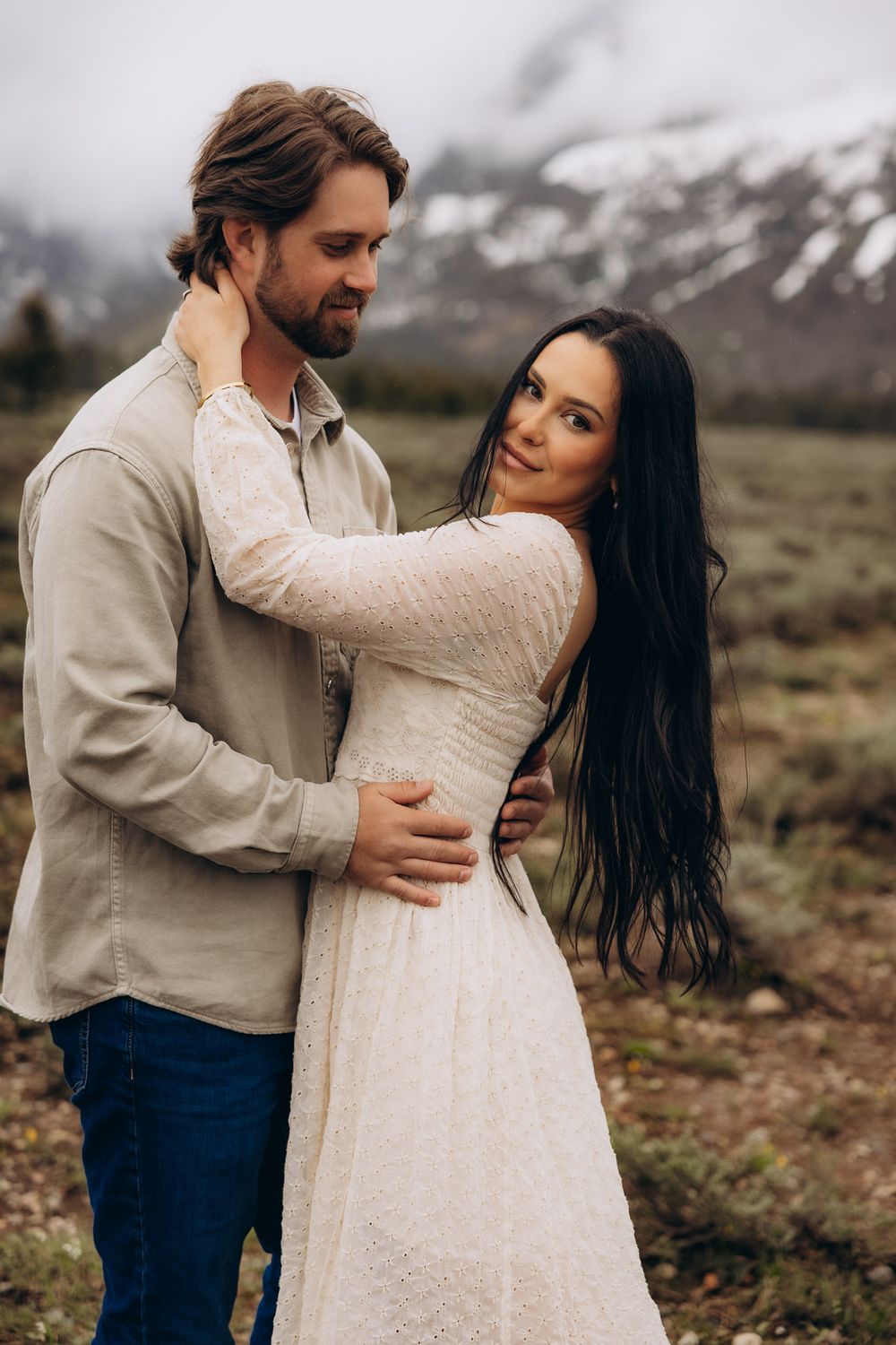 A romantic couple embraces in an outdoor mountain setting during a fall engagement photo session.