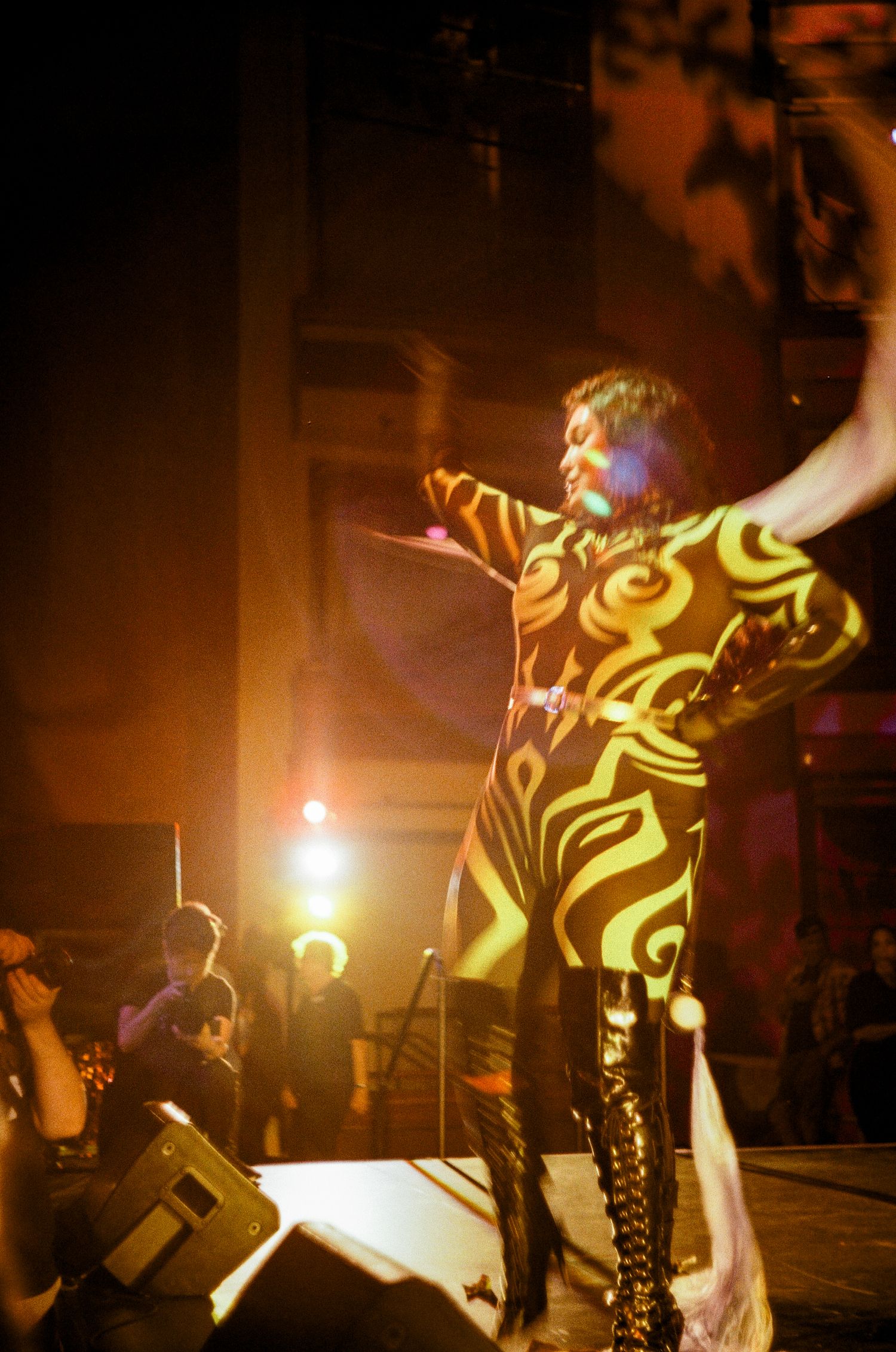 A performer in shiny boots dances energetically on stage during a concert performance across multiple action shots.