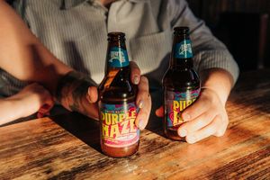 Two bottles of Double Hell craft beer on a wooden table in a bar setting.