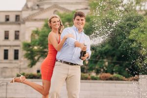 Romantic couple dances together in formal attire near a fountain at an elegant outdoor venue.