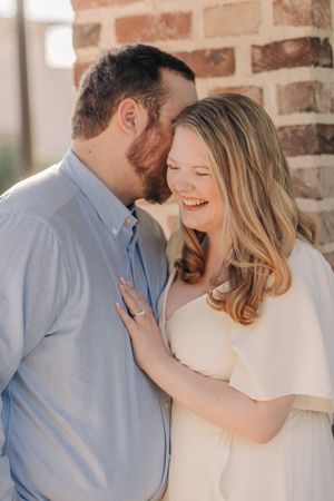 A romantic outdoor portrait session against a brick wall with soft lighting.