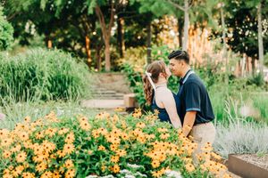 Couple enjoys a romantic moment together in a lush garden filled with vibrant orange flowers and greenery.