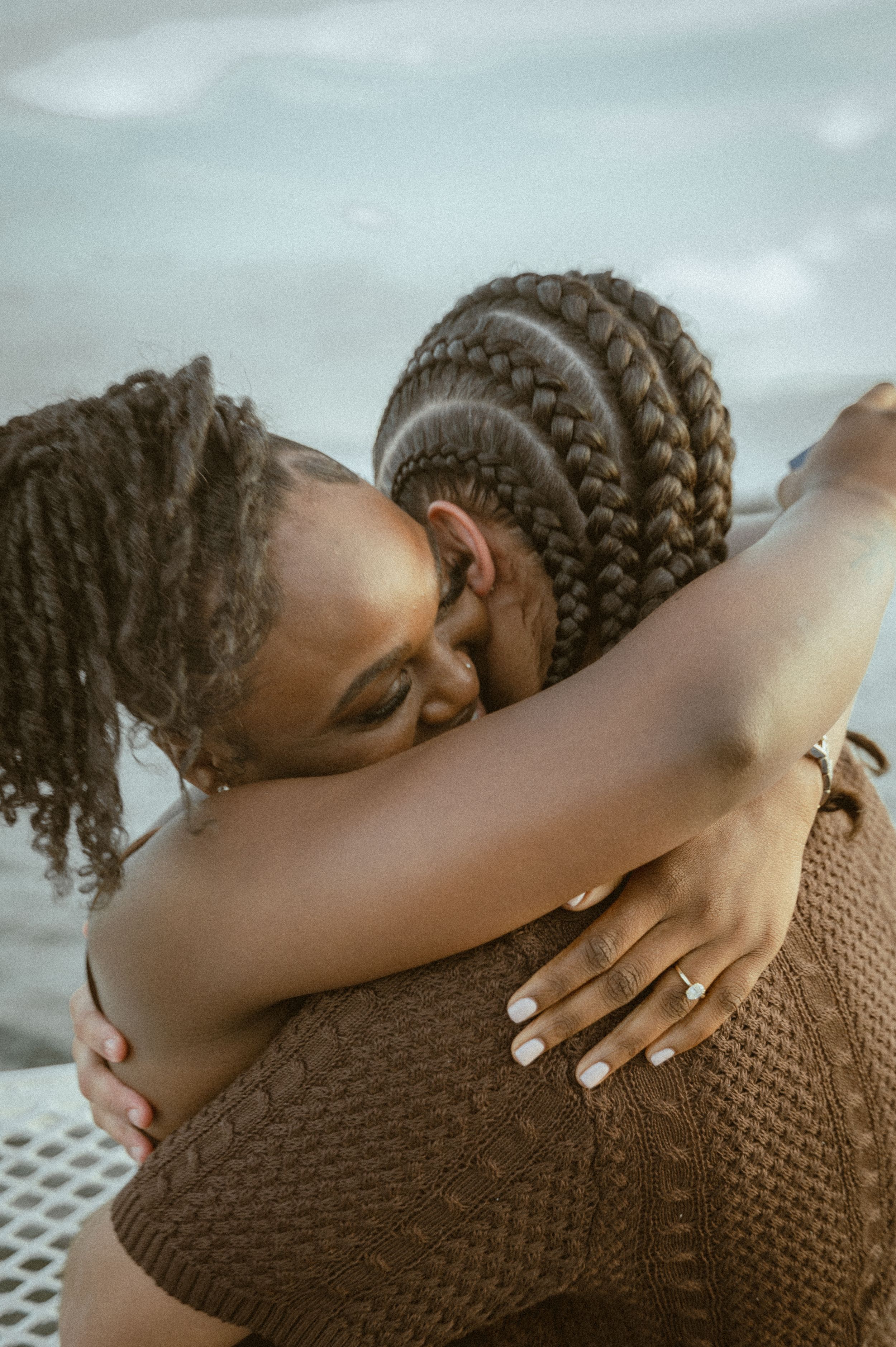 An intimate embrace shared on a boat deck with water visible in the background.