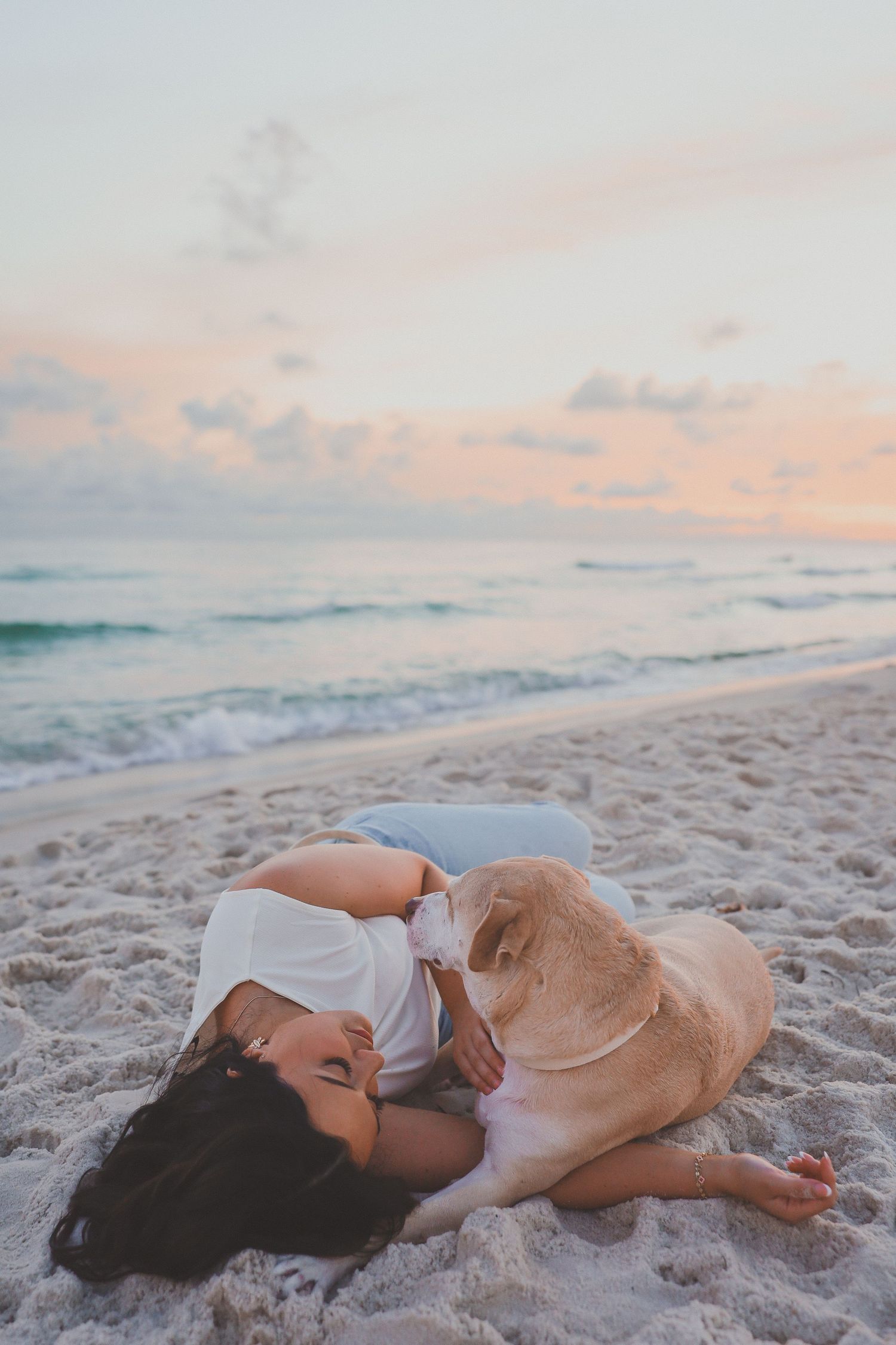 Happy couple embracing and laughing together on a beach during a beautiful golden sunset.