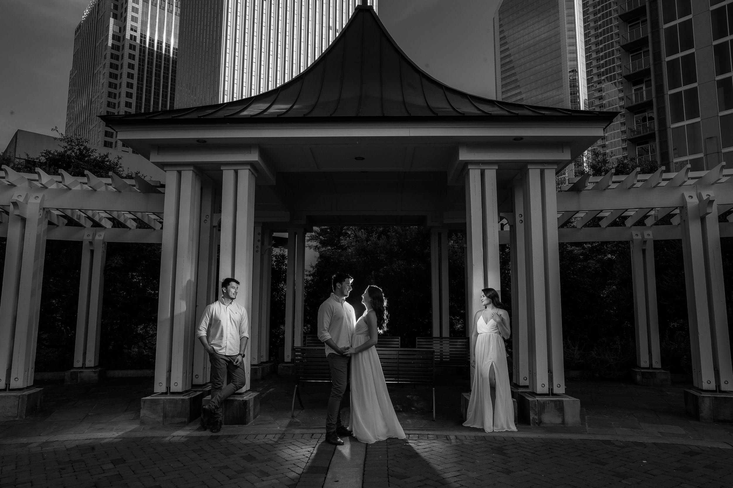 Dramatic black and white wedding portrait under Asian-inspired pavilion with modern city backdrop.