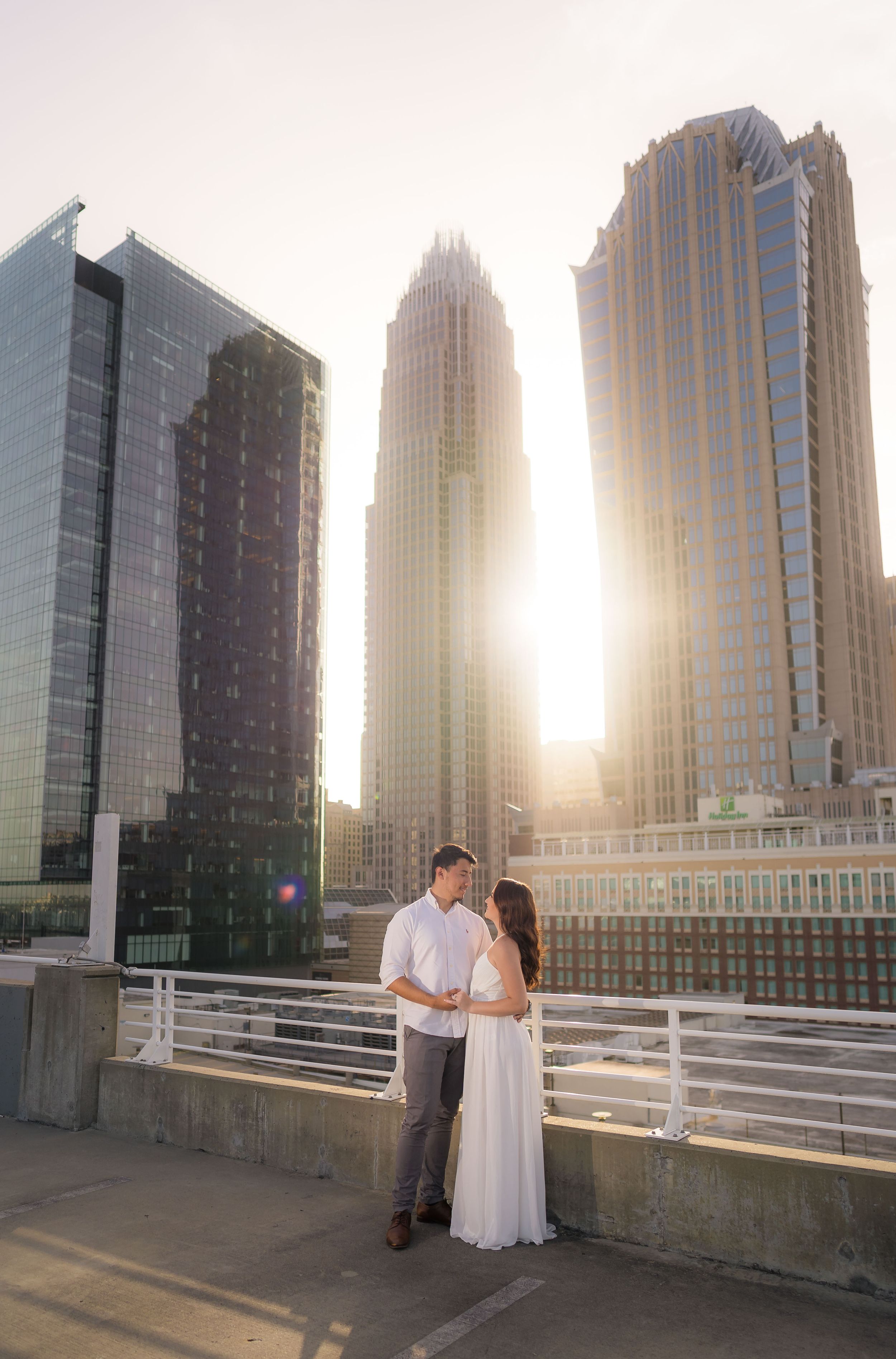 Romantic sunset engagement photo with Charlotte skyline backdrop.