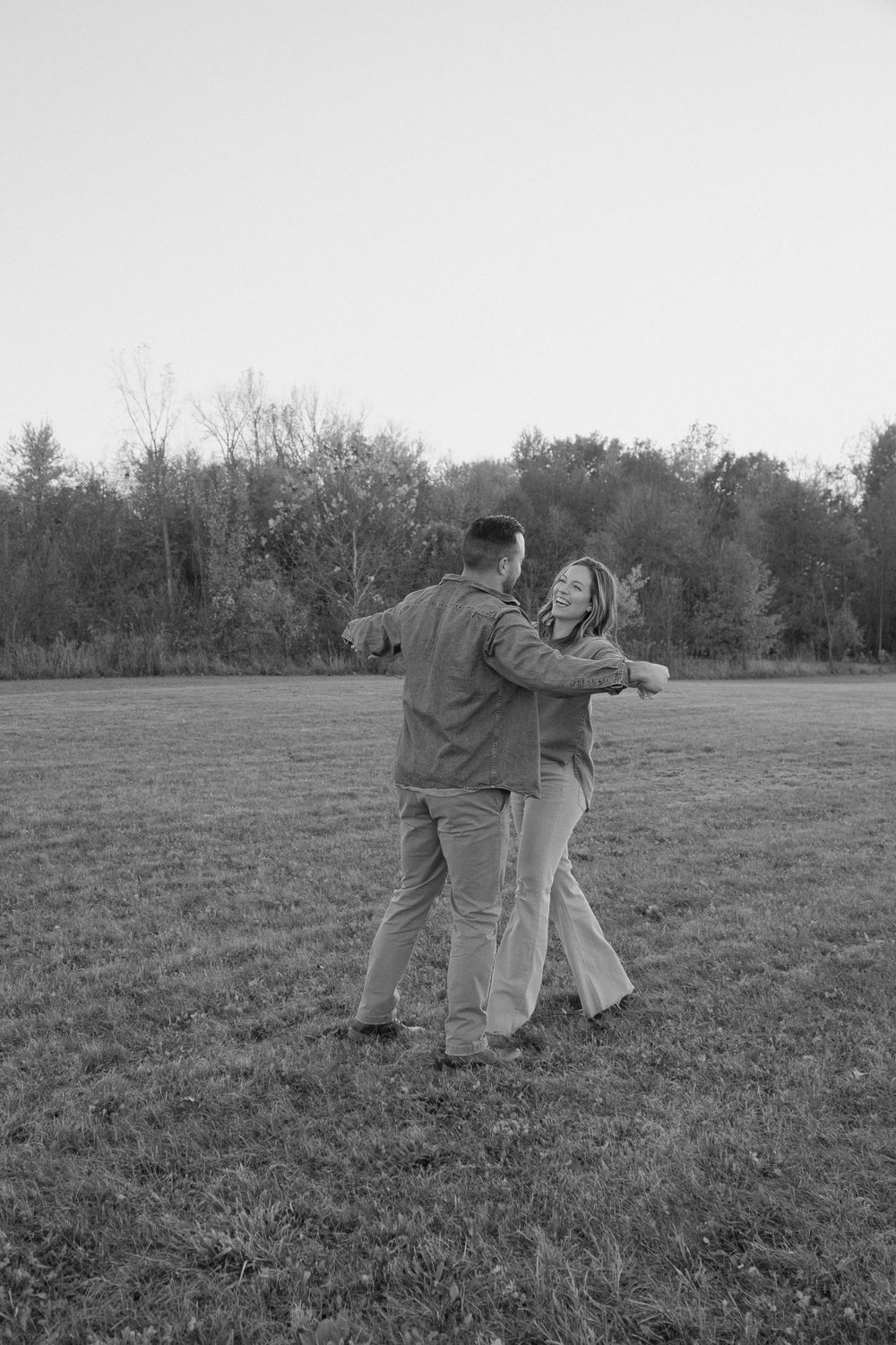 A black and white photo of a couple dancing in an open field.