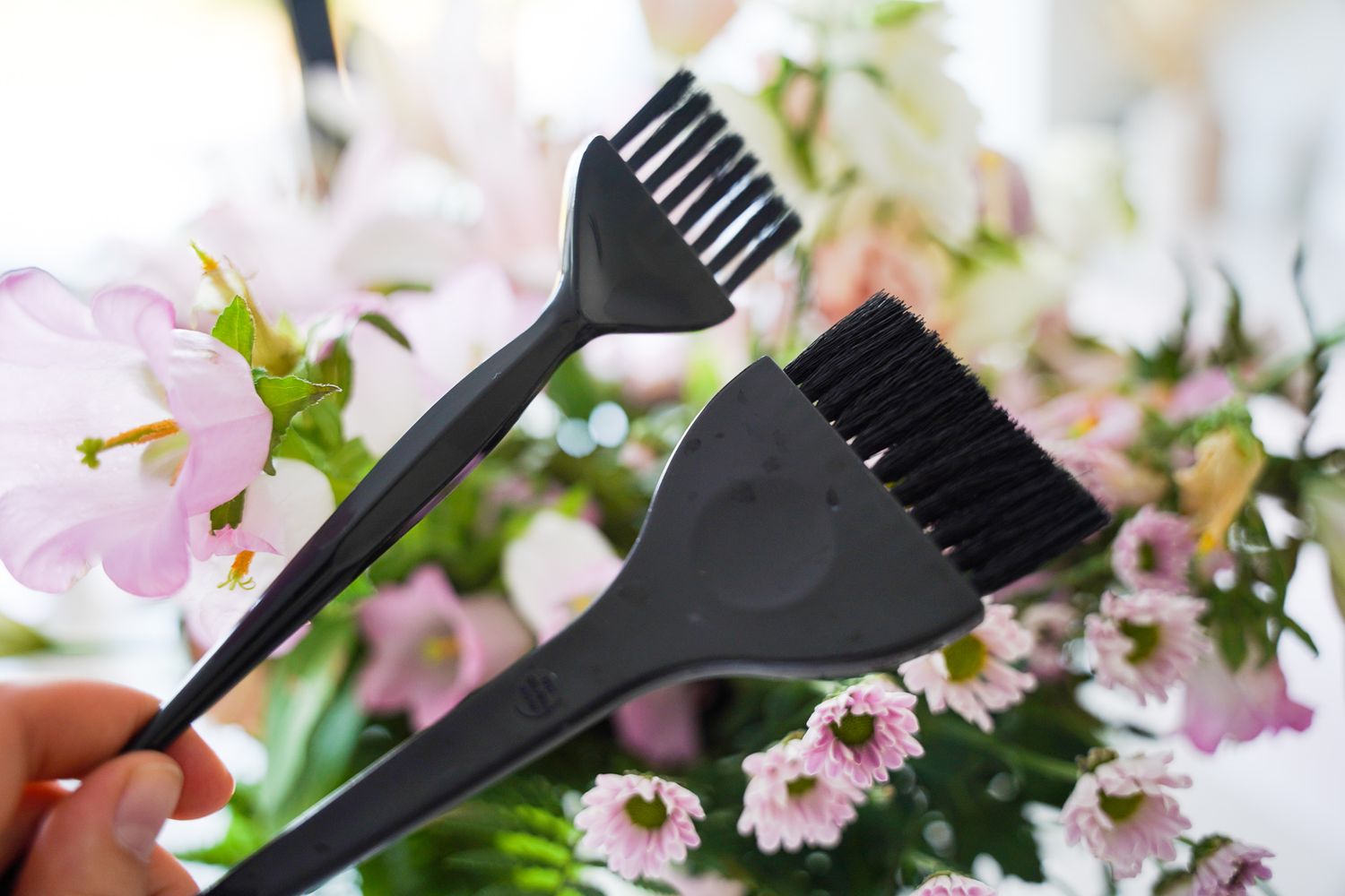 Black hair dye application brushes with pink cherry blossoms in the background.