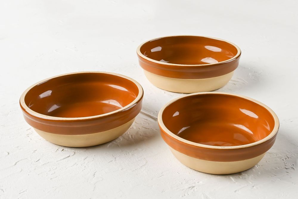 Three terracotta bowls with two-tone design on white surface.