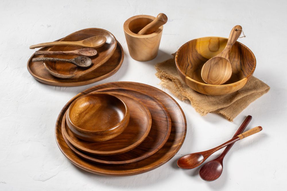 Collection of handcrafted wooden bowls and spoons arranged on white surface.