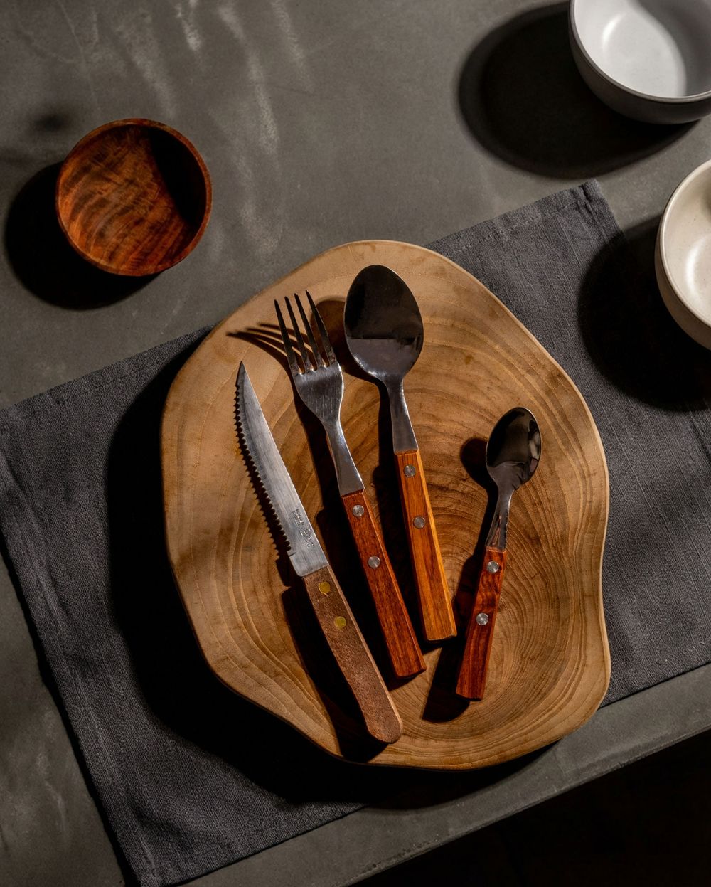 Wooden plate with rustic cutlery set including knife, fork and spoons with wooden handles.