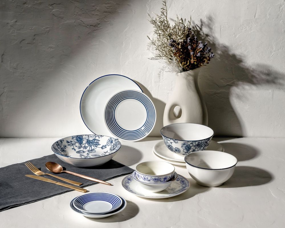 Collection of white and blue porcelain plates and teacups arranged in dramatic lighting.