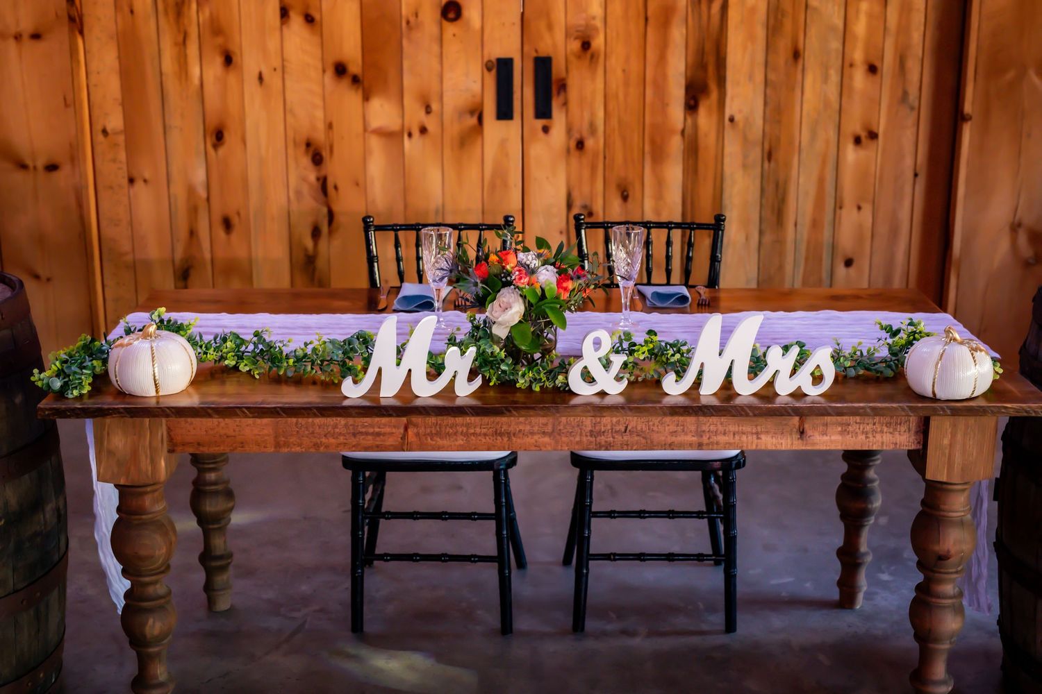 Wedding sweetheart table with Mr & Mrs signs decorated with pumpkins and floral arrangements.