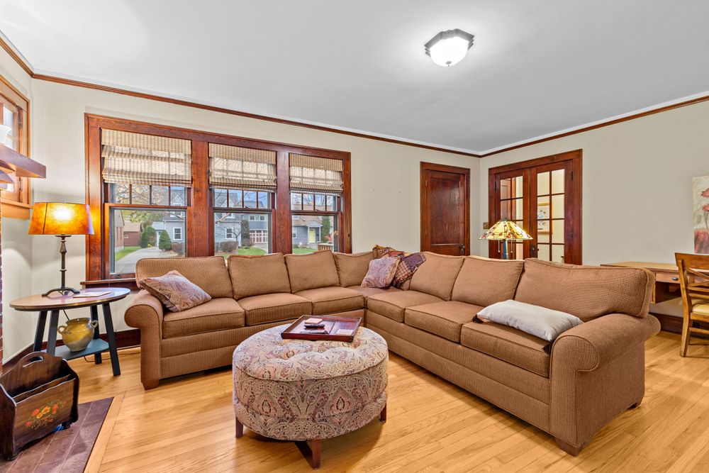Spacious living room with large L-shaped sectional sofa, hardwood floors, craftsman-style wood trim, and natural light.