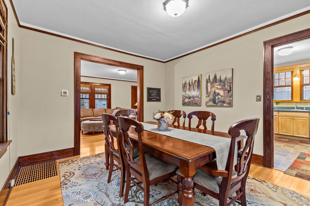 Elegant dining room with wooden table set, area rug, hardwood floors, and view into adjacent living spaces.