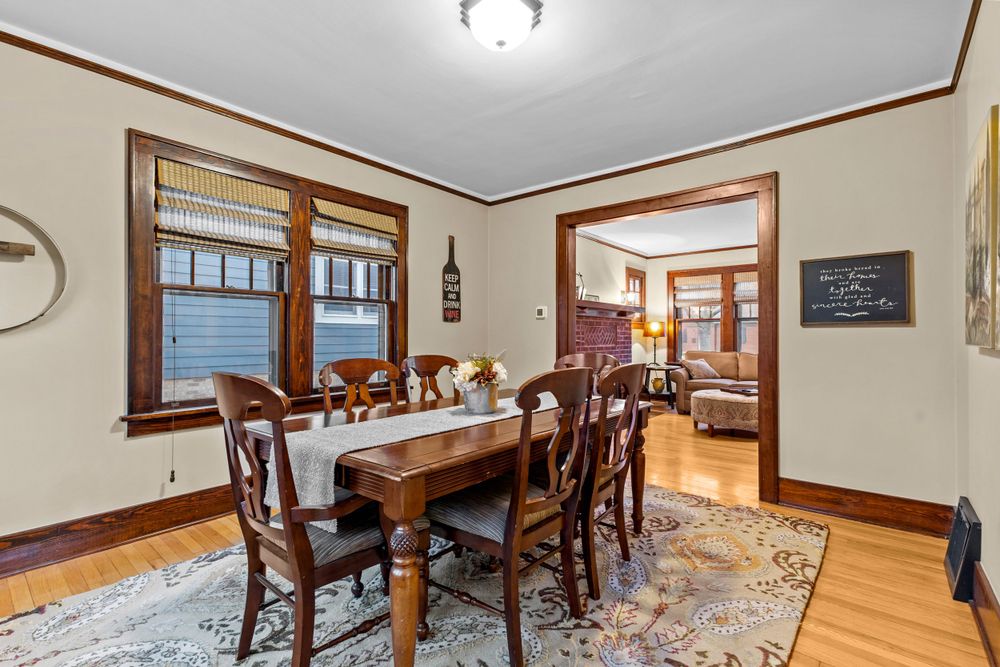 Classic dining room featuring wooden dining set, decorative area rug, craftsman wood trim, and natural lighting.