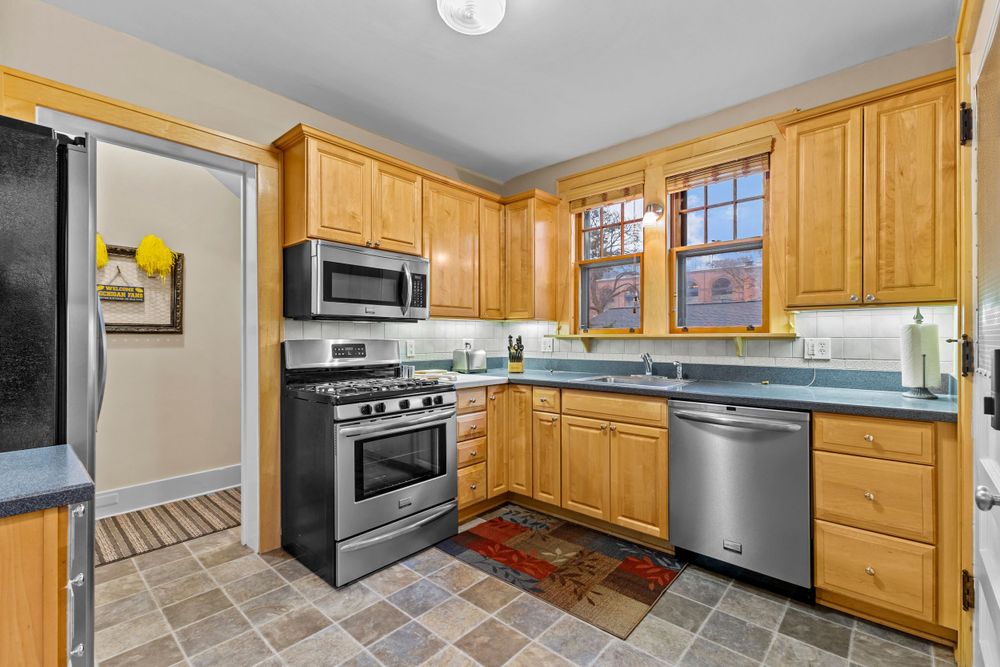 Updated kitchen with honey oak cabinets, stainless steel appliances, tile floors, and dark countertops.