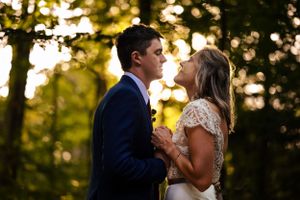 Bride and groom share a golden hour moment together in a sun-dappled forest after their ceremony.