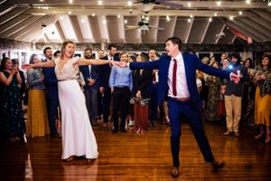 Bride and groom energetically dance together on a wooden dance floor at their wedding reception.