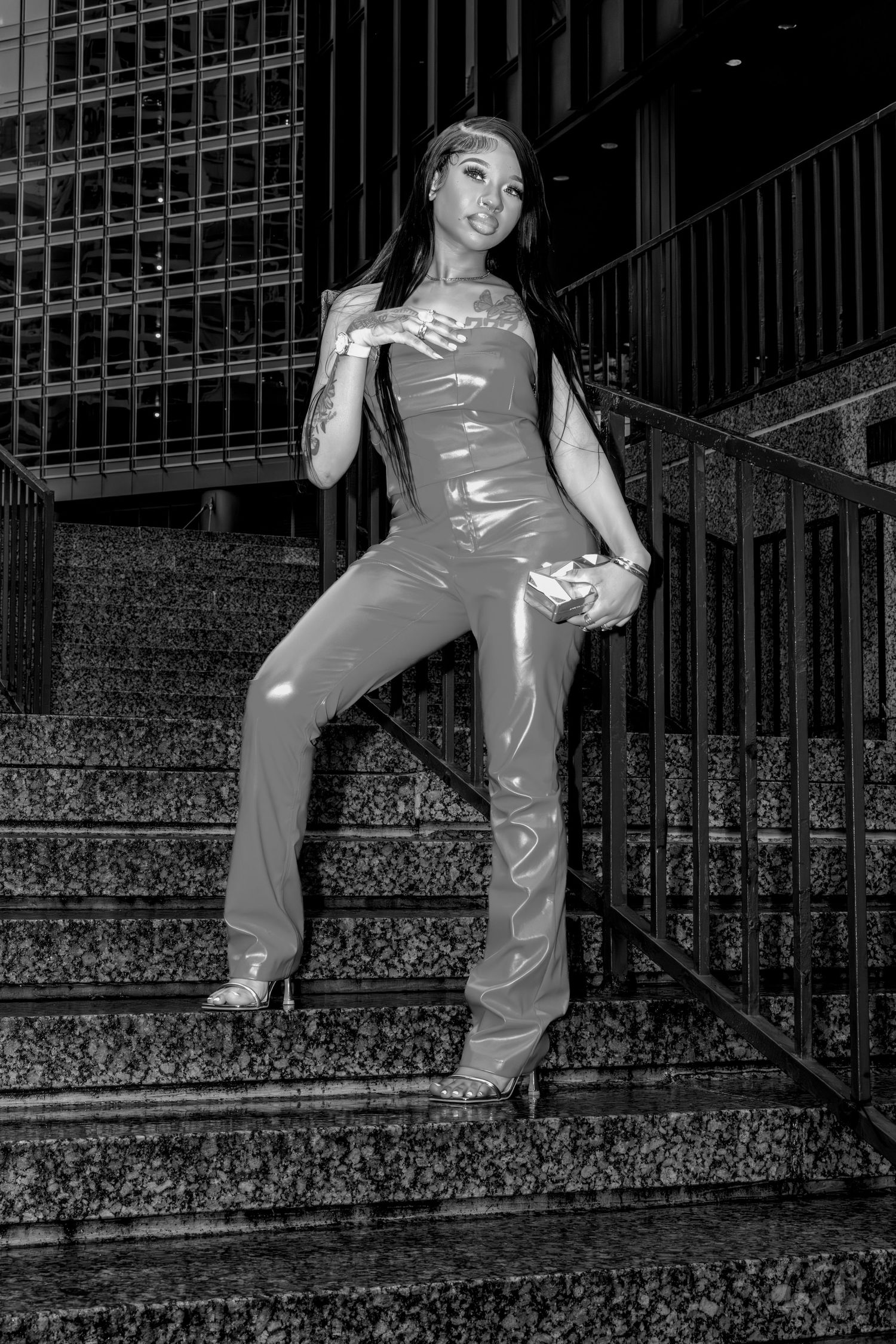 Person in shiny outfit posing dramatically on outdoor steps in urban setting.