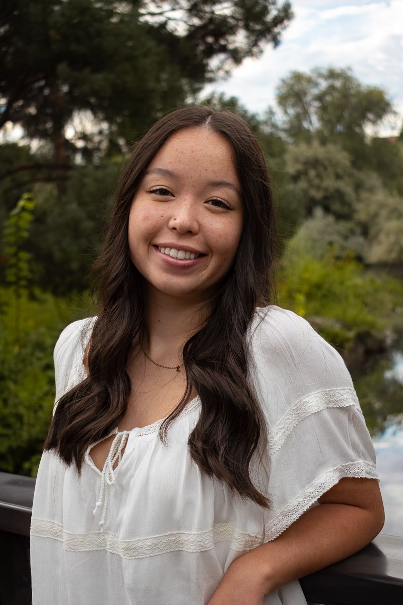 A portrait featuring someone in a white peasant blouse against a natural background.