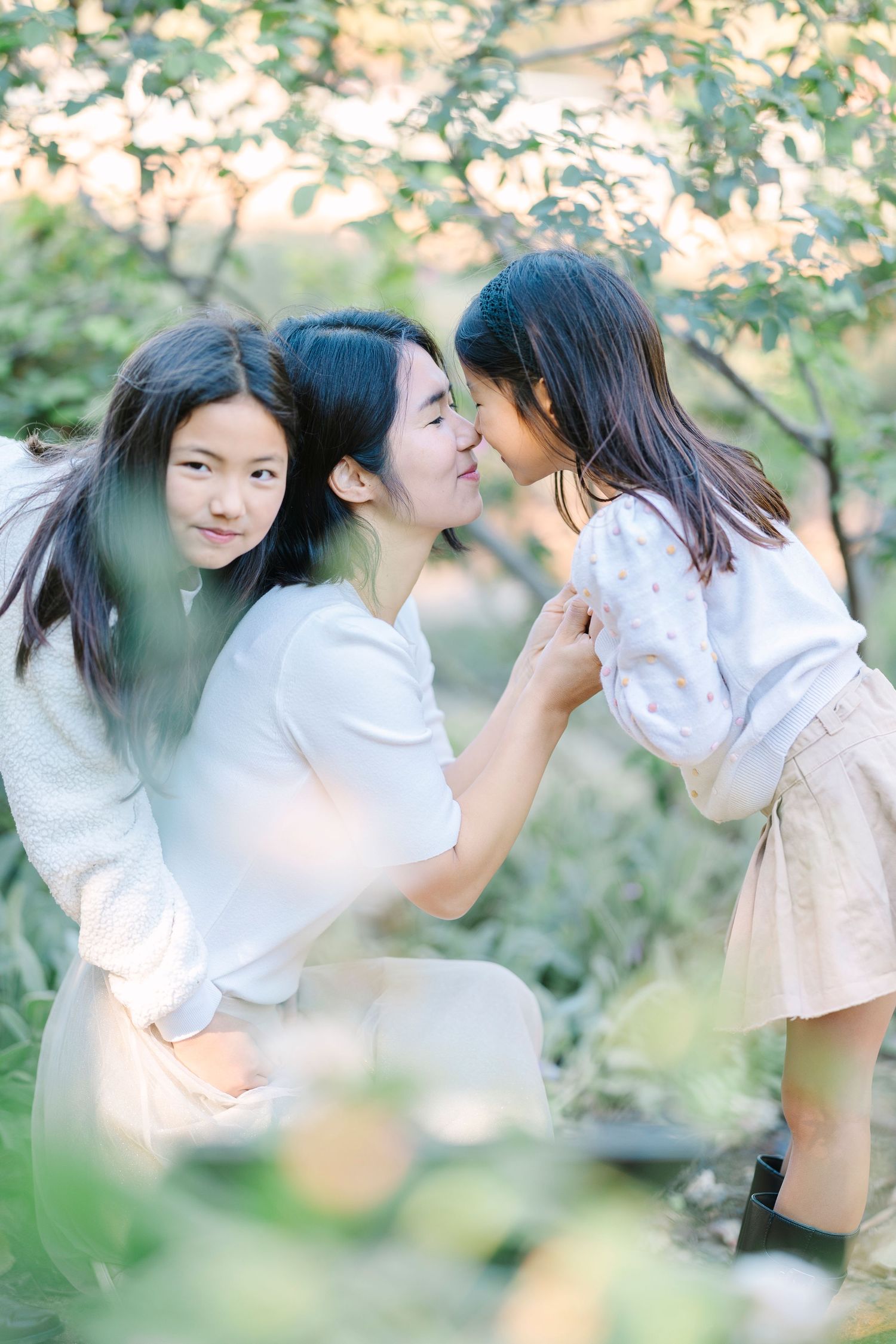 An intimate family moment captured outdoors with natural lighting and foliage.