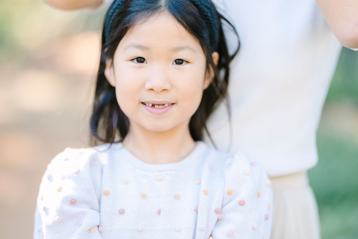 A close-up portrait in soft natural lighting with greenery in the background.