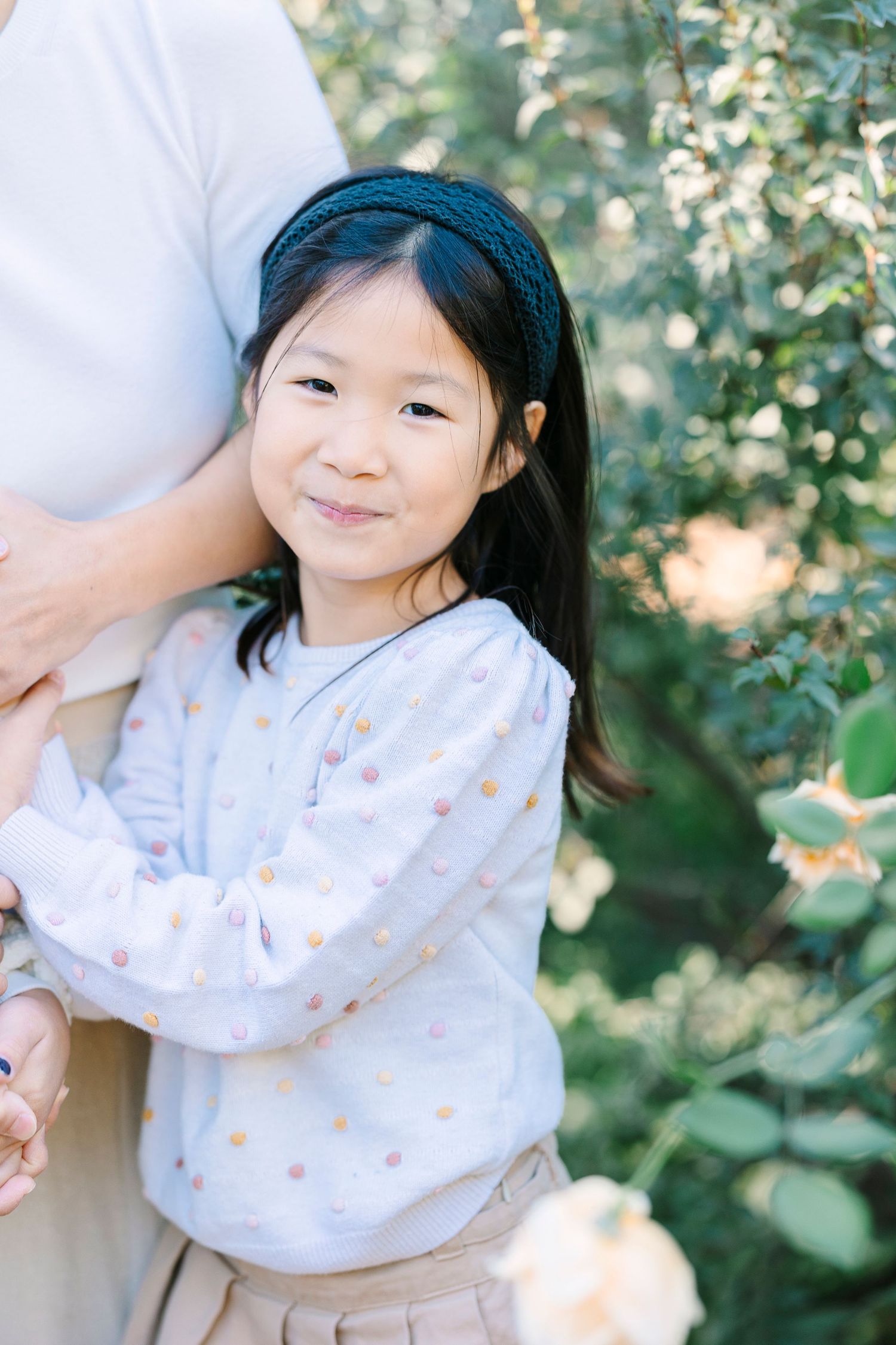 A sweet portrait in natural lighting with greenery and soft bokeh effects.