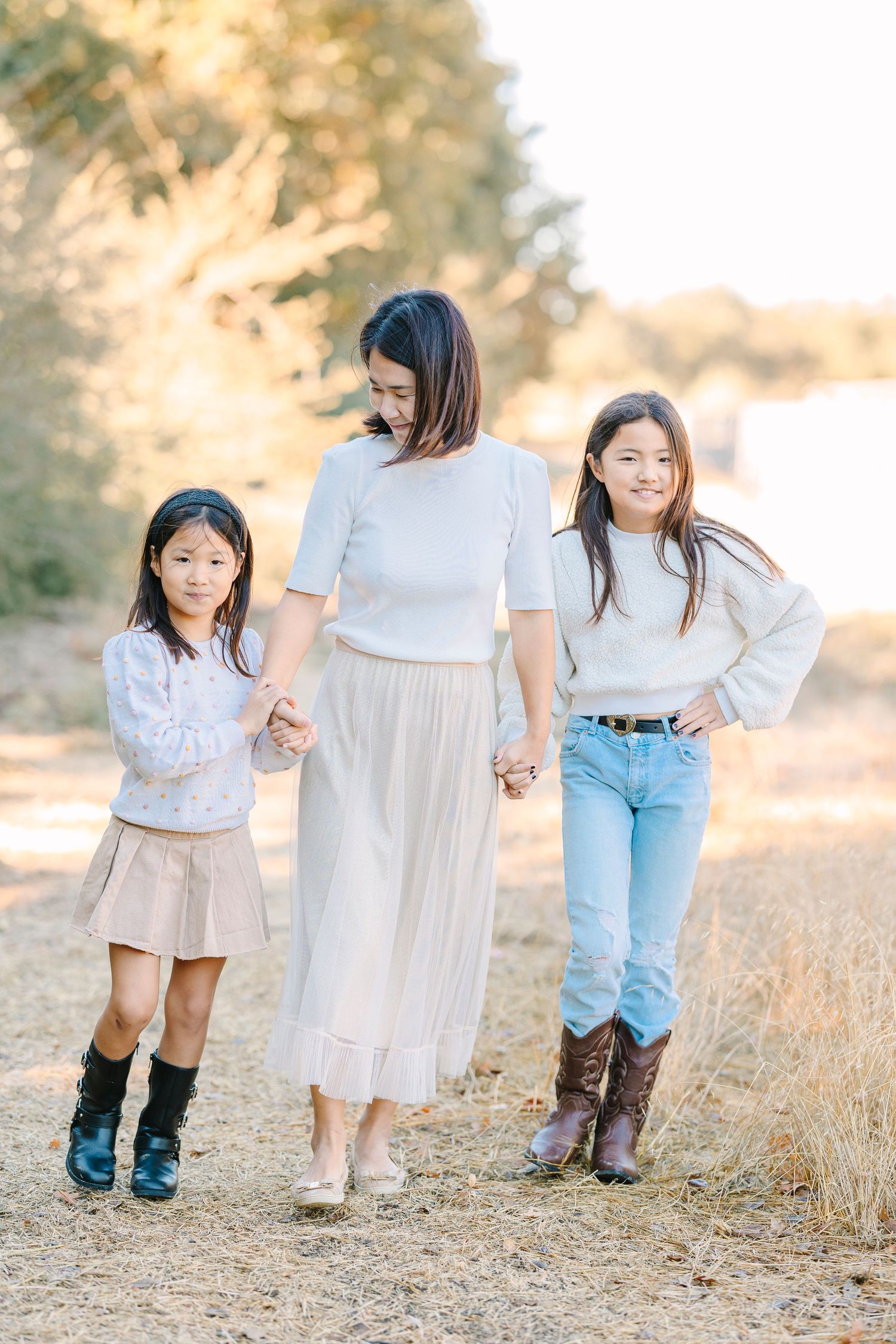 People wearing coordinated white outfits and boots walk together in a sunny field.