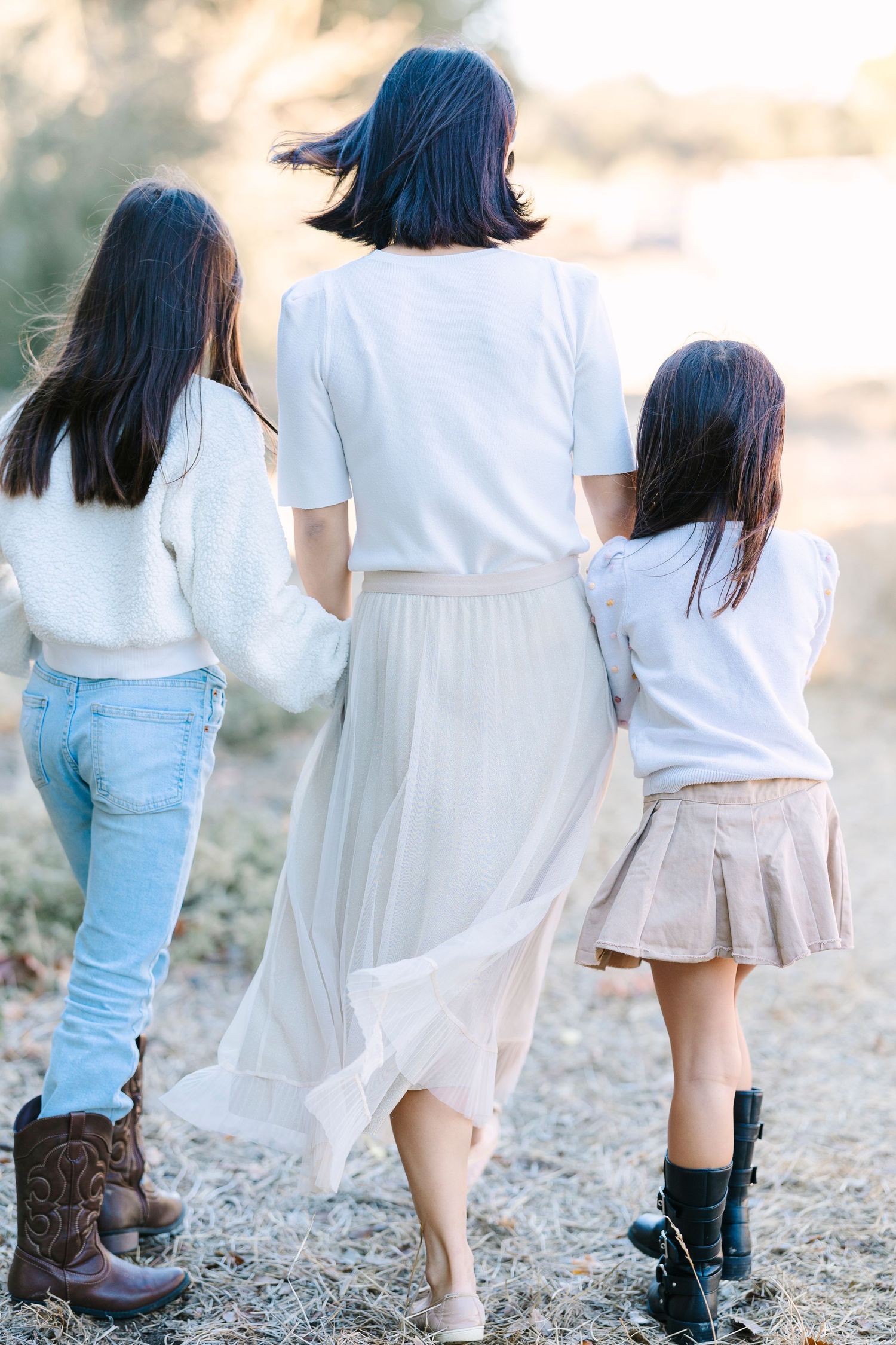 People in white tops and denim walk together on a rocky path during golden hour.
