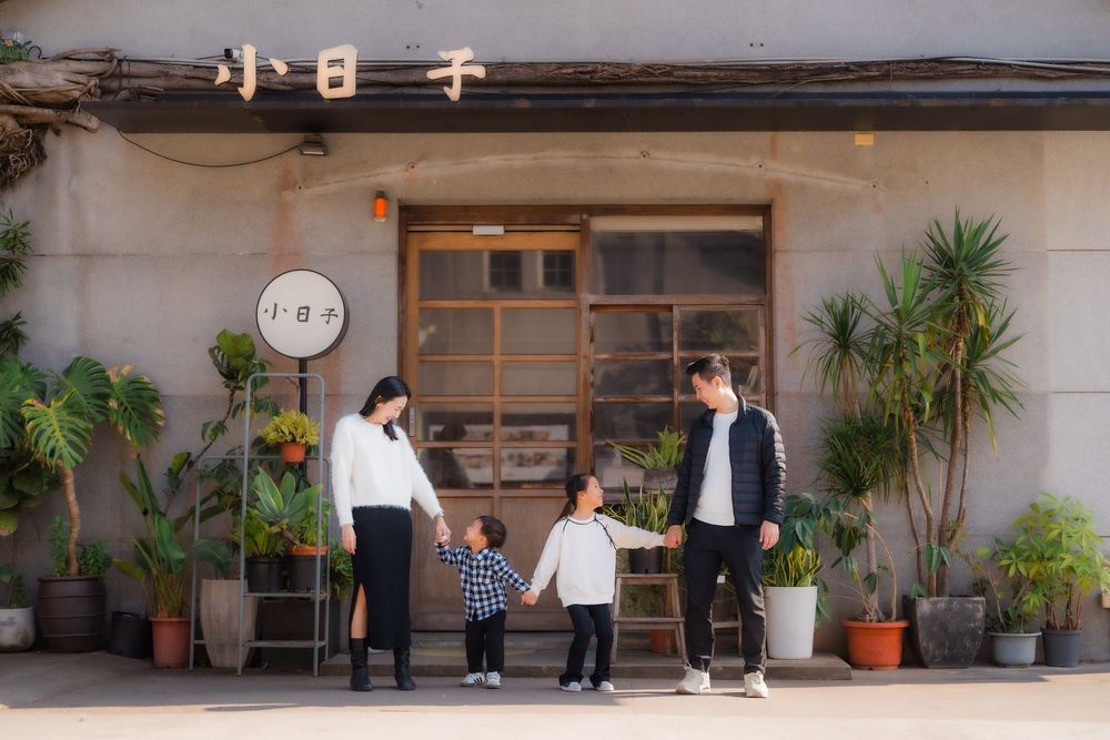 Family standing together outside an industrial modern building entrance green plans and wooden accents at Huashan Creative Park.
