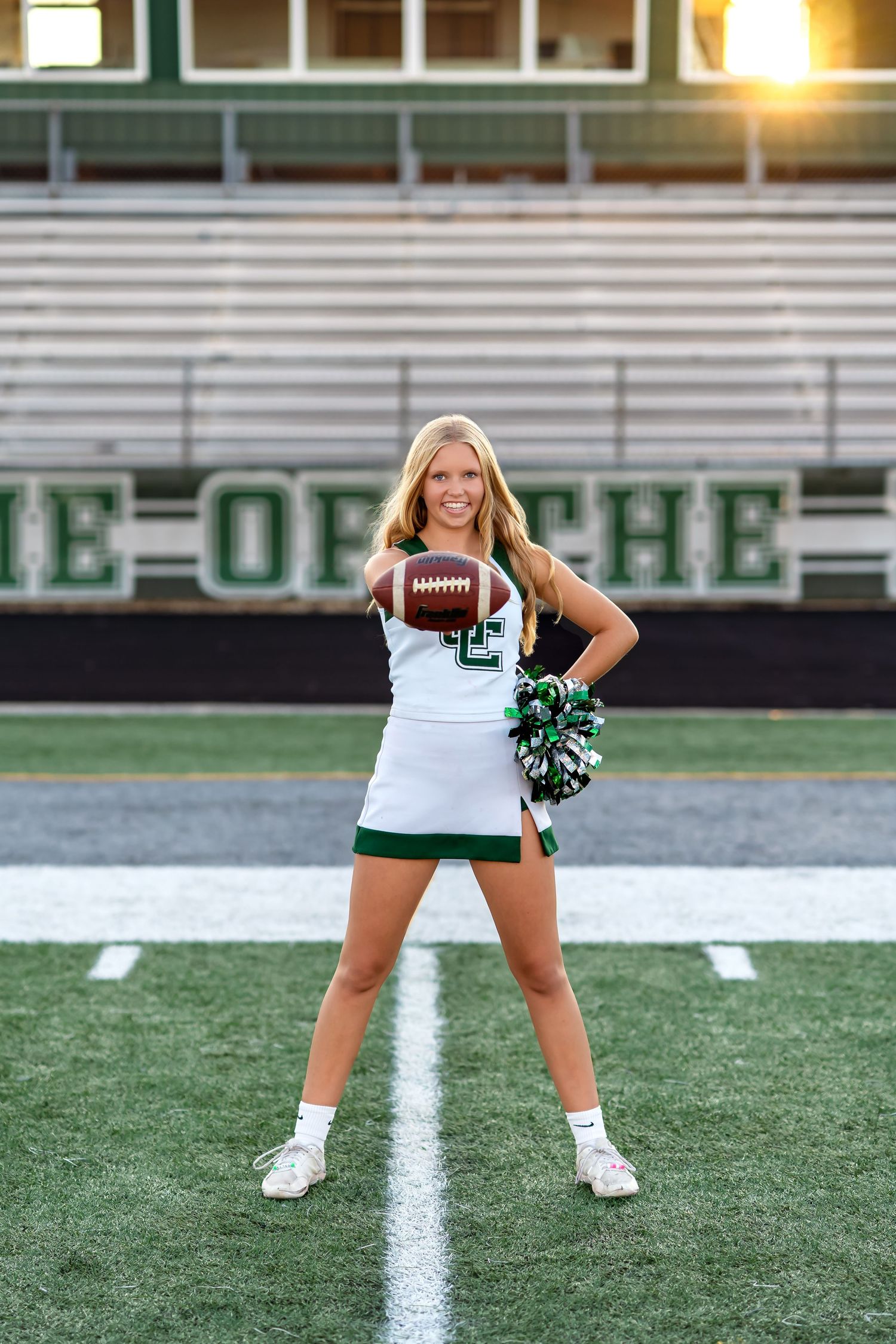 A cheerleader strikes dynamic poses with pom poms on a football field during golden hour lighting.