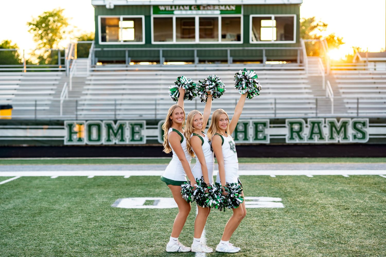 Cheerleaders perform synchronized routines on a football field during golden hour at their home stadium.
