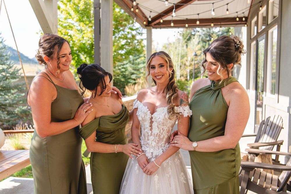 Tearful bride sharing joyful reactions with bridesmaids on outdoor patio with string lights.