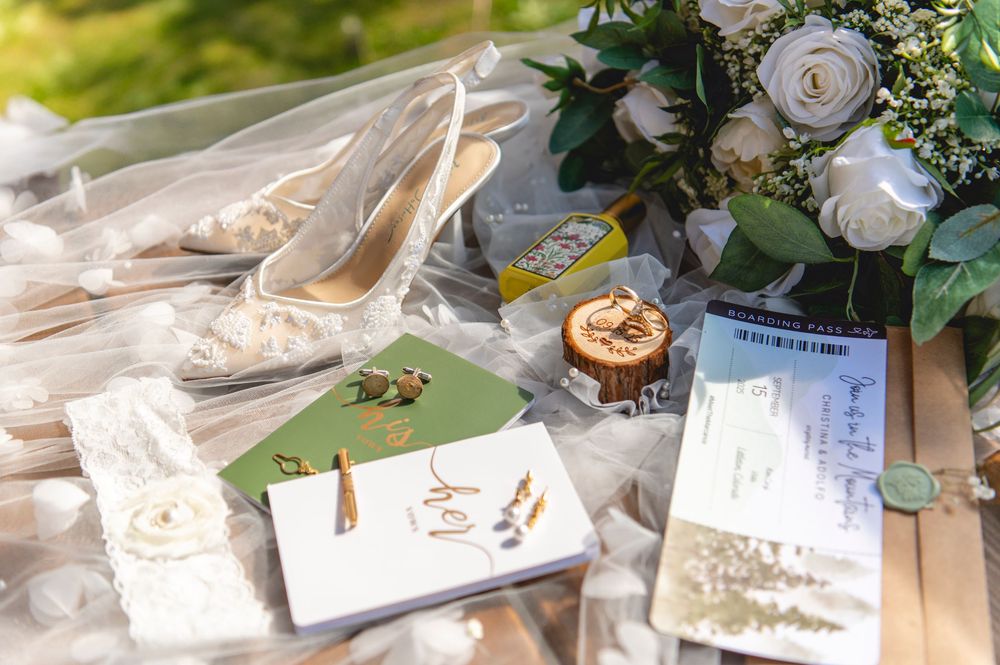 Wedding invitations placed alongside delicate white roses and soft greenery in an elegant flat lay arrangement.