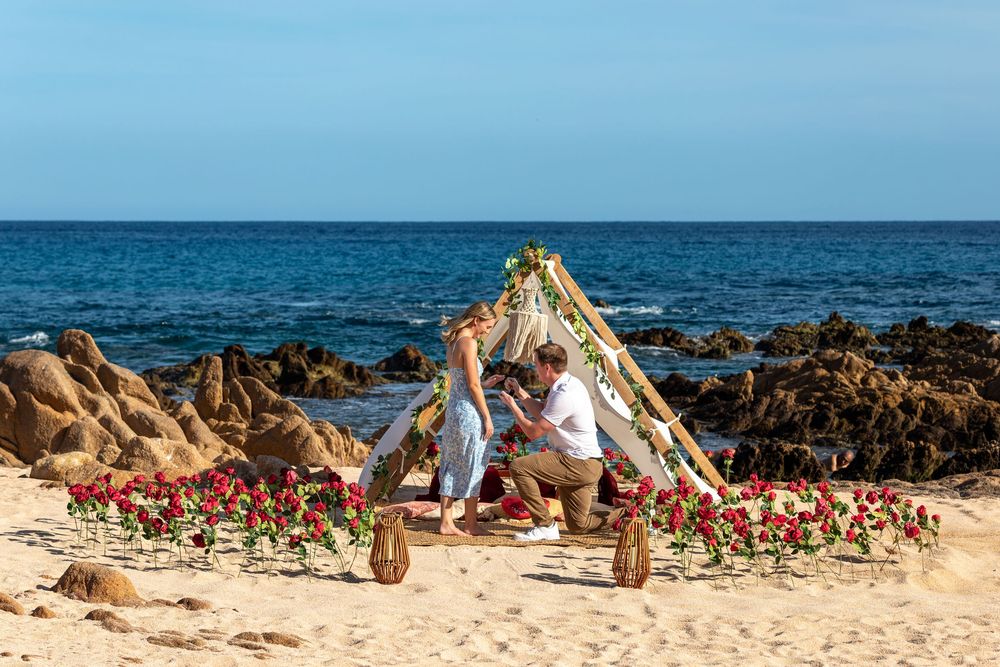 Scenic beach landscape with lei garlands and traditional Hawaiian decorations laid out on golden sand by the ocean.