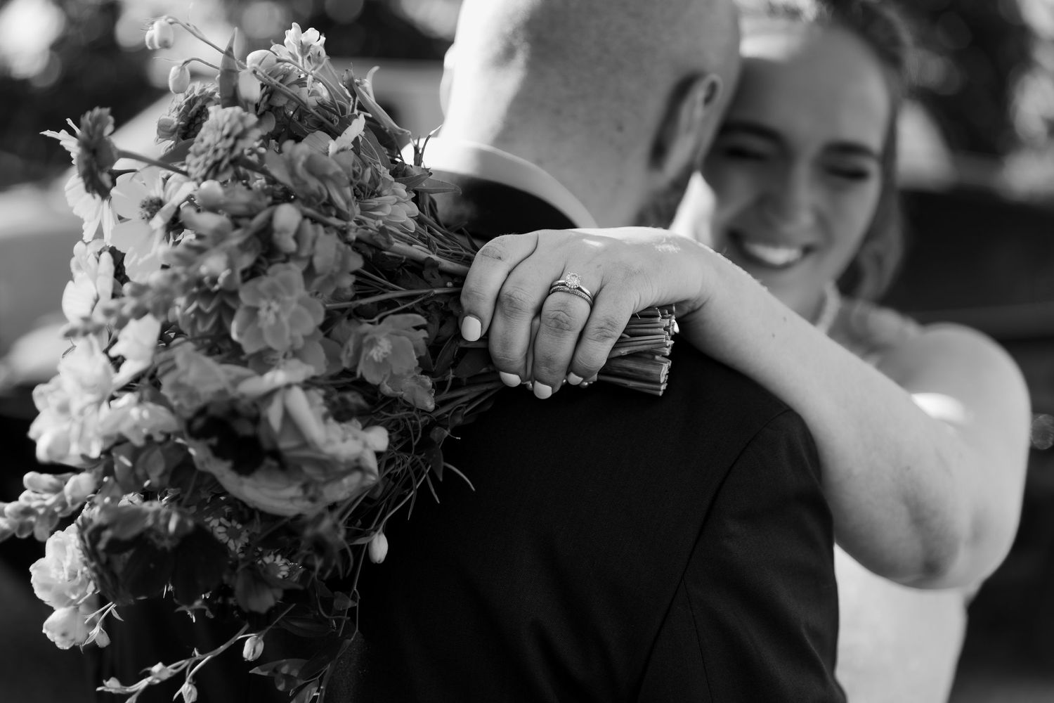 Bride and groom snuggle their heads close together while bride showcases her rings and flowers at Hauser Hall in Kitchener, Ontario.